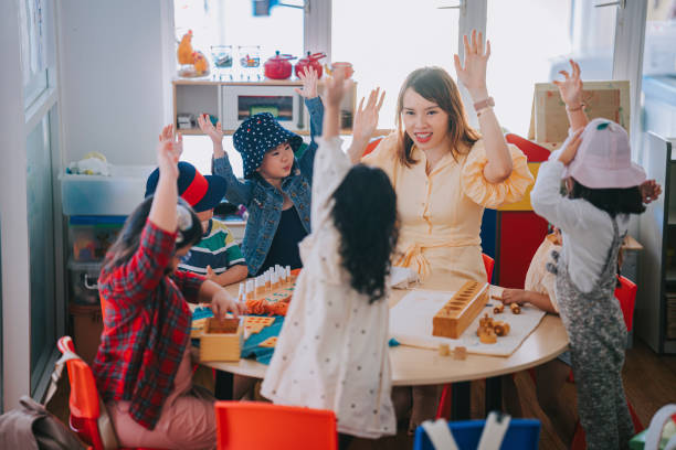 Asian Montessori preschool student raised hands in the class answering question Asian Montessori preschool student raised hands in the class answering question teachers stock pictures, royalty-free photos & images