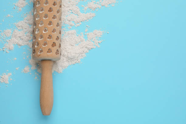 istock Wooden rolling pin and flour on light blue background, top view. Space for text 1407068717