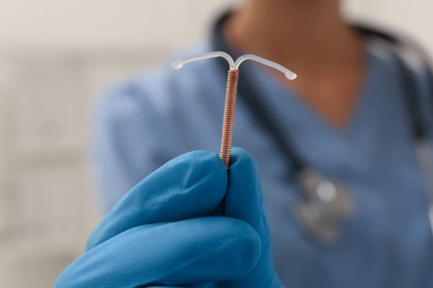 médecin tenant un dispositif contraceptif intra-utérin en forme de t sur fond flou, gros plan - iud photos et images de collection