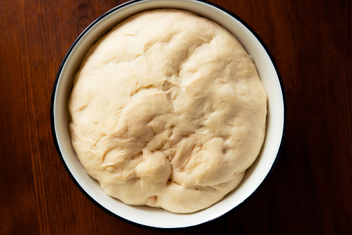 yeast dough for bread or pizza on a floured surface, with flour splash. Cooking bread.