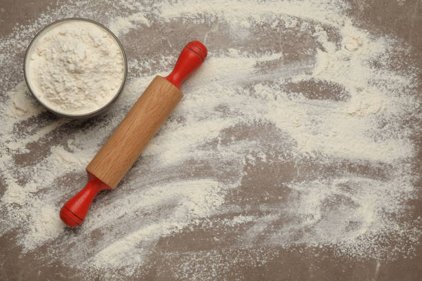 istock Wooden rolling pin and bowl with flour on grey background, flat lay. Space for text 1407069474