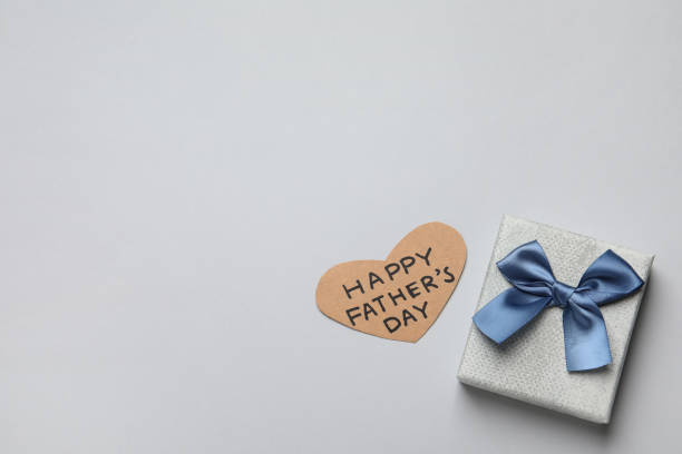 istock Heart shaped card with phrase HAPPY FATHER'S DAY and gift box on light grey background, flat lay. Space for text 1407071483