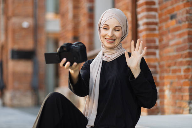 istock Young muslim woman using a video camera to record video for her work. 1407071711