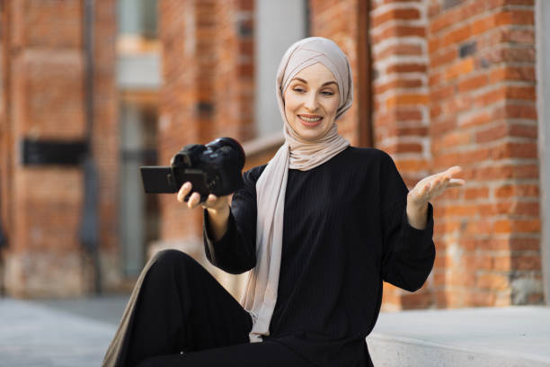 istock Young muslim woman using a video camera to record video for her work. 1407071716