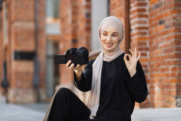 istock Young muslim woman using a video camera to record video for her work. 1407071718