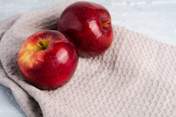 istock Juicy fresh red apples with water drops on kitchen towel on grey background with copy space 1407071886