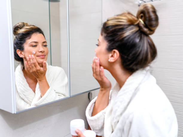 istock Woman in a bathrobe applying skin moisturizer 1407072037