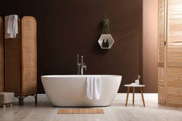 istock Modern ceramic bathtub with towel near brown wall in room 1407072831