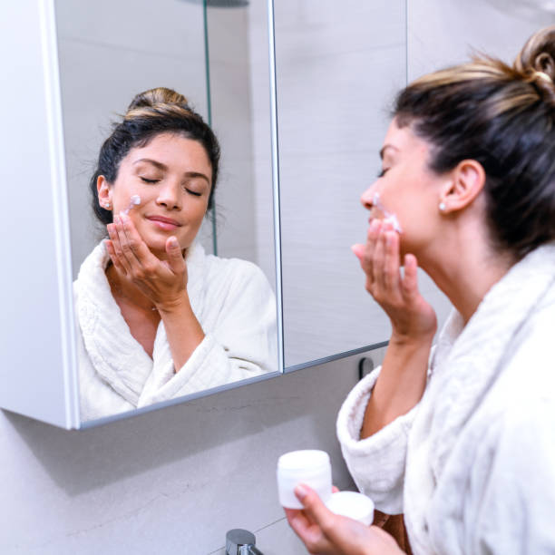 istock Woman in a bathrobe applying skin moisturizer 1407072993