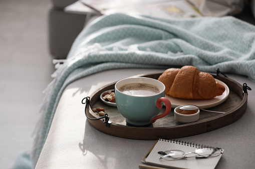 Tray with tasty breakfast on grey sofa in morning.  Space for text