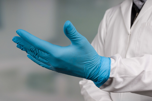 hand with medical gloves  in front of a clinic room