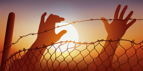 Symbol of migrant and oppressed peoples, with outstretched hands behind barbed wire. Concept of freedom and human rights with raised hands behind a fence and barbed wire, a symbol of oppressed peoples. nazism stock illustrations