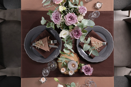 Elegant table setting with beautiful floral decor and burning candles, top view