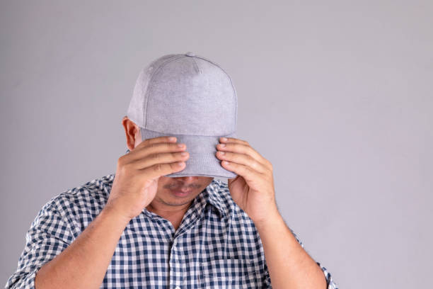 istock Man wearing grey cap and hidden his face from camera on grey background 1407077499