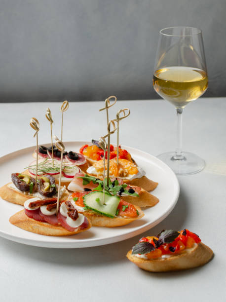 brushetta, antipasti  or authentic traditional spanish tapas set with glass of wine . variety of  pinchos (pintxos) in a bar or restaurant or home party - bruschetta buffet party food imagens e fotografias de stock