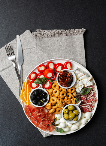Classic italian antipasti or tapas wine snacks set. Cheese variety, black and green olives, pickles, prosciutto di Parma, tomatoes, salami, tarallini. Flat lay, top view, copy space for text