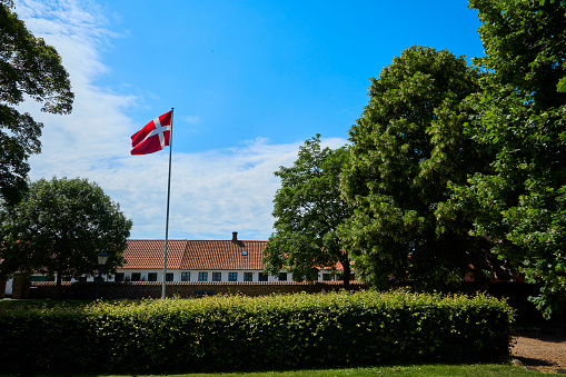 Park and houses. Hedges and trees around red flag \