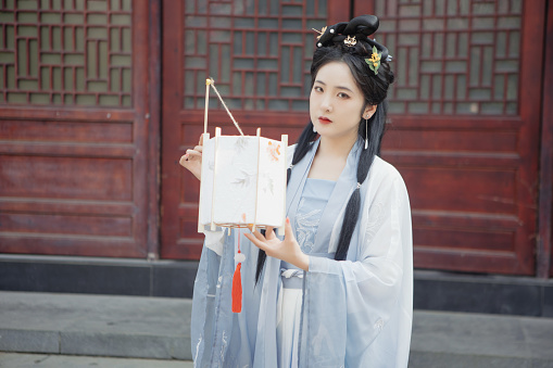 Chinese Hanfu beauties carry lanterns outdoors in spring
