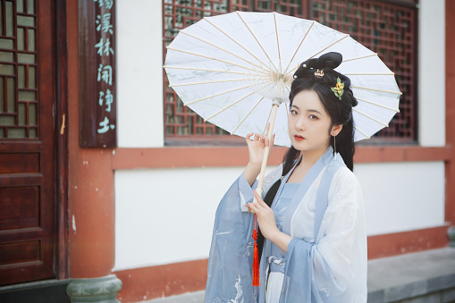 Chinese Hanfu beauties hold umbrellas outdoors in spring