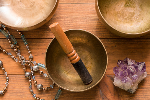 Top view of a still life with bronze singing bowls on a wooden table. The singing bowls are used in meditation and music therapy sessions.