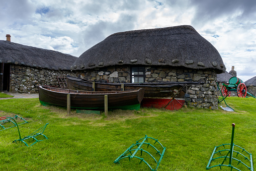 Kilmuir, United Kingdom - 1 July, 2022: the Skye Museum of Island Life in Kilmuir on the coast of the Isle of Skye with thatched crofter cottages and boats