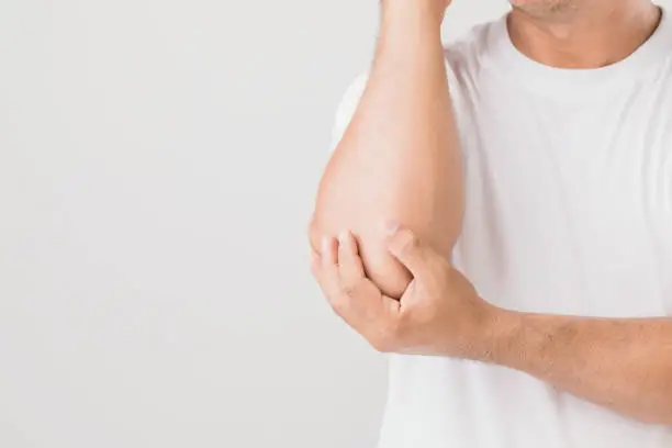 Elbow pain concept : Close up man holding on elbow and feeling a pain. Studio shot isolated on grey background with copy space for text