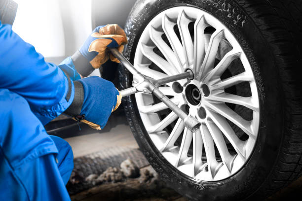 istock Man mechanic with car tire in service center. 1407081722
