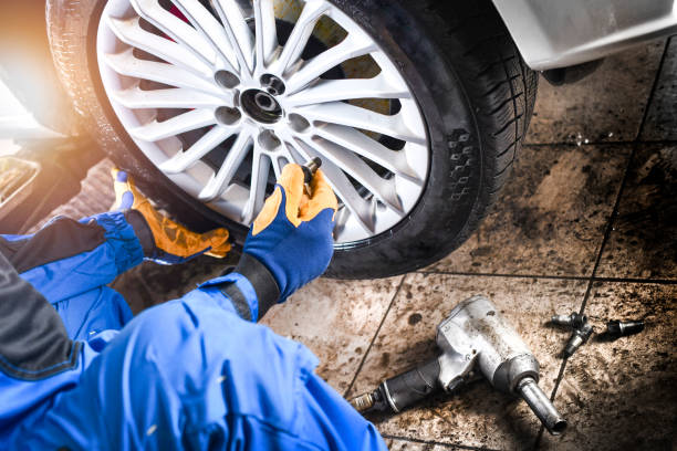 istock Man mechanic with car tire in service center. 1407081725