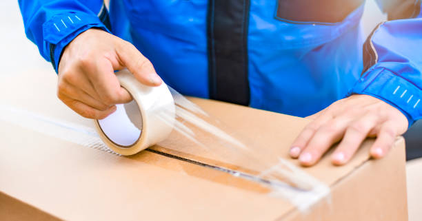 istock Worker hands holding packing machine and sealing cardboard or paper boxes 1407081766