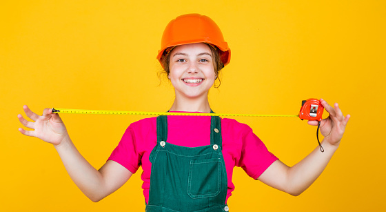 This will be perfect. kid wear helmet on construction site. teen girl builder with building tool tape measure. child on repairing work. concept of renovation in workshop. busy professional carpenter.