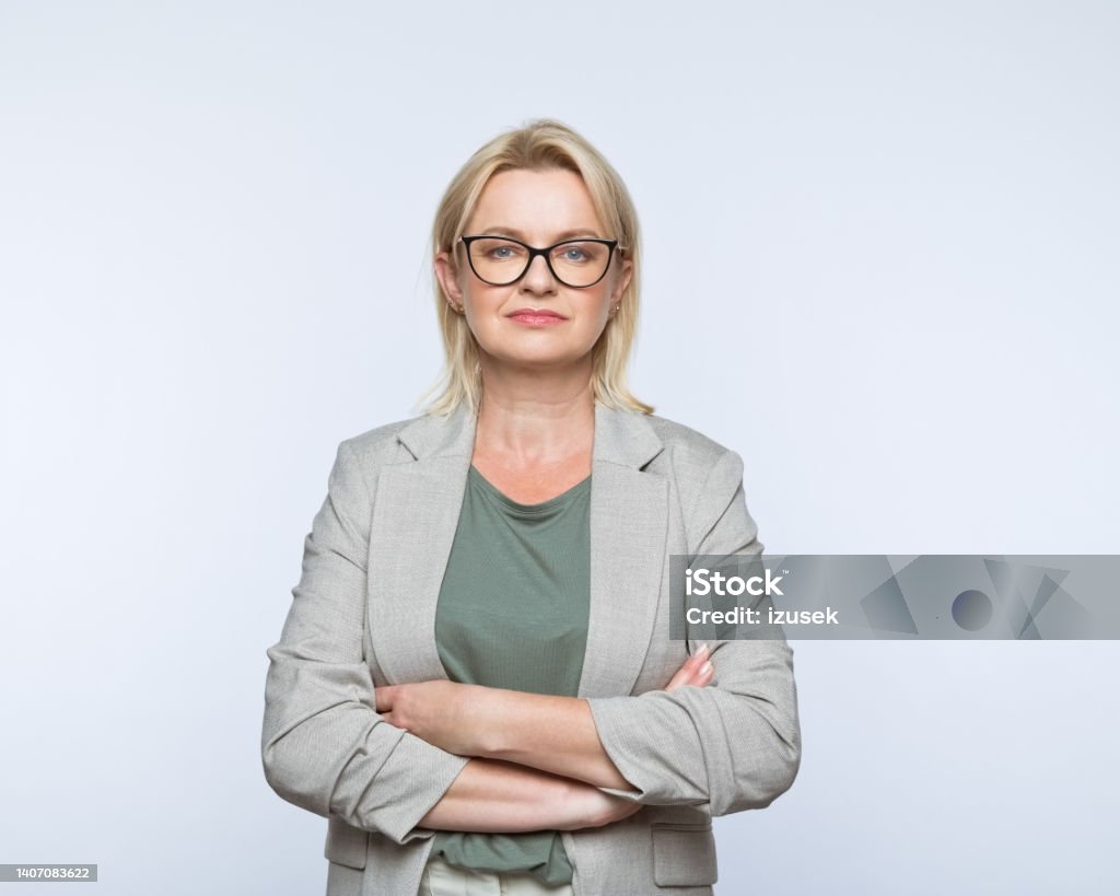 Portrait of confident mature women Portrait of confident mature businesswoman wearing smart casual looking at camera. Studio shot, grey background. One Woman Only Stock Photo