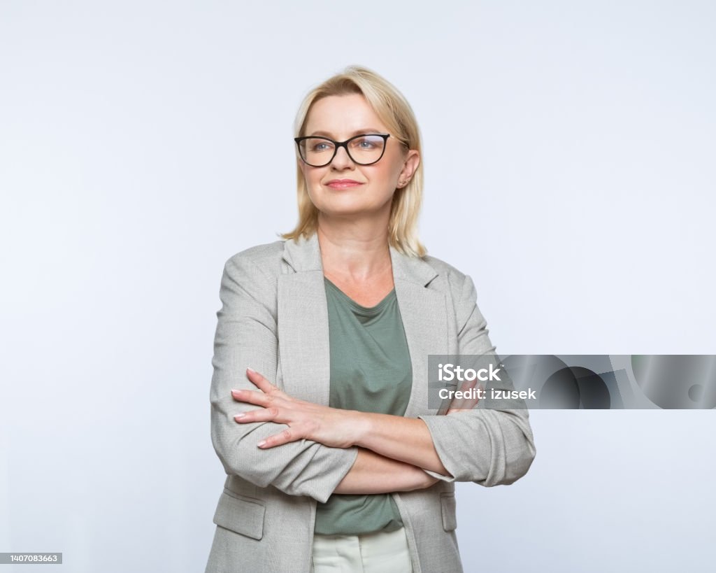 Portrait of confident mature women Portrait of confident mature businesswoman wearing smart casual looking away and smiling. Studio shot, grey background. Looking Away Stock Photo