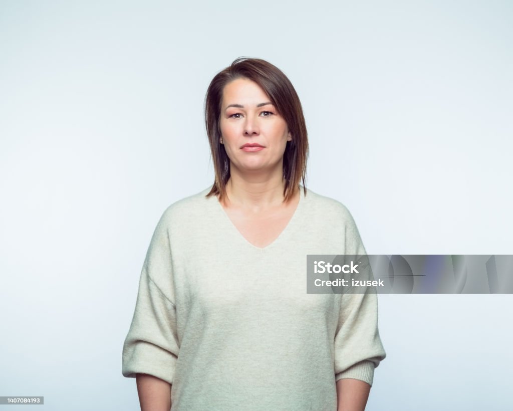 Portrait of confiedent woman Portrait of mid adult woman wearing casual looking at camera. Studio shot, grey background. Serious Stock Photo