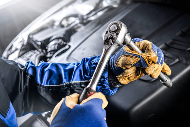 Auto mechanic working on car broken engine in mechanics service or garage. Transport maintenance wrench detial.