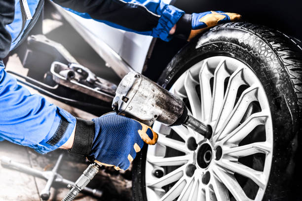 istock Man mechanic with car tire in service center. 1407084510
