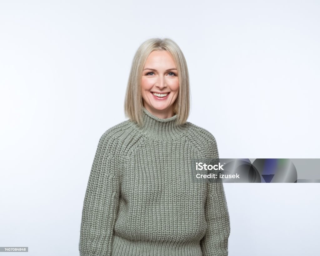 Portrait of smiling mature women Portrait of confident mature woman wearing khaki sweater, smiling at camera. Studio shot, grey background. 40-49 Years Stock Photo