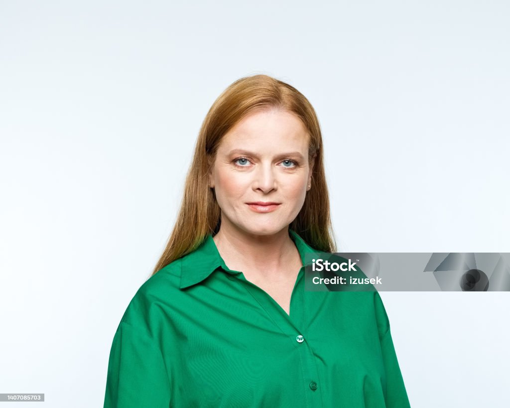 Portrait of smiling mature women Portrait of confident mature woman wearing green shirt, smiling at camera. Studio shot, grey background. 40-49 Years Stock Photo