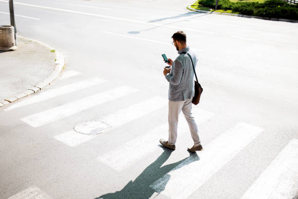 istock Confident businessman passing crosswalk using phone 1407085706