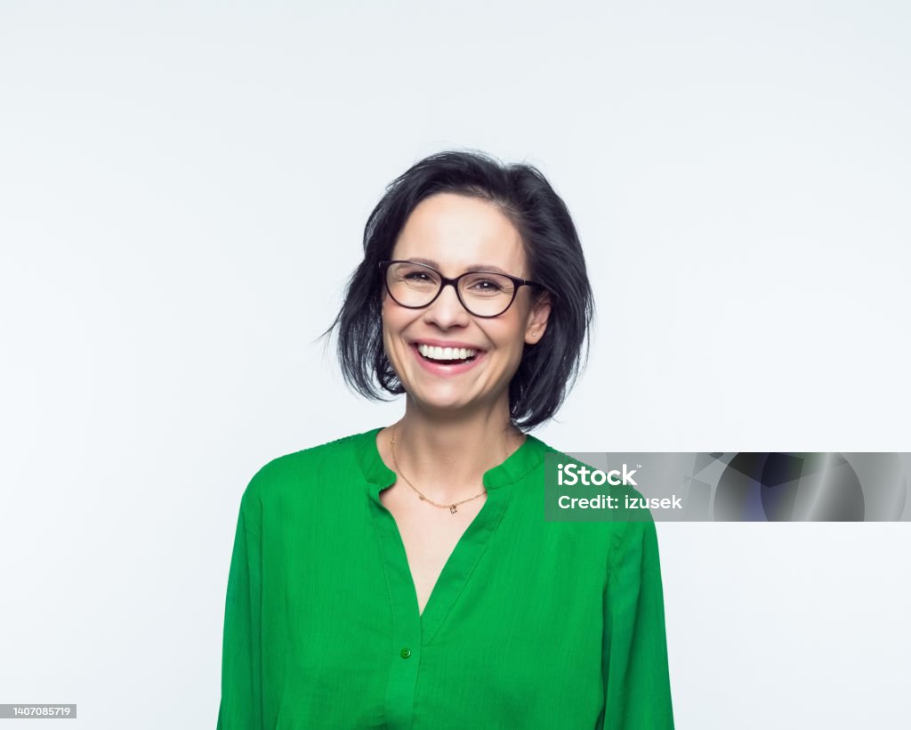 Portrait of smiling mature women Portrait of confident mature woman wearing green dress, smiling at camera. Studio shot, grey background. Mature Women Stock Photo