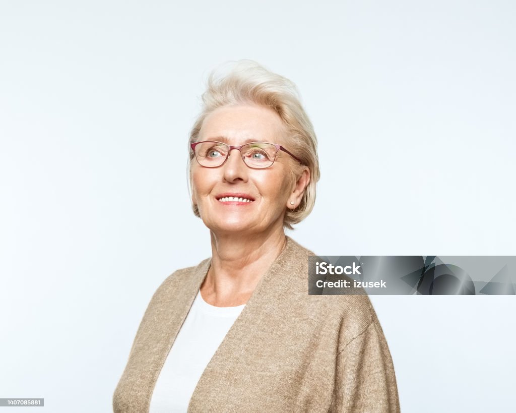 Portrait of smiling senior women Portrait of confident senior woman looking away and smiling. Studio shot, grey background. 70-79 Years Stock Photo