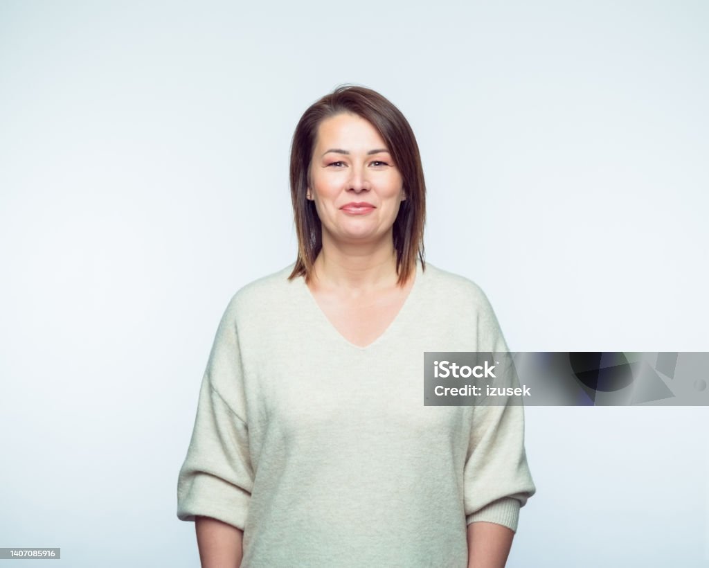 Portrait of smiling woman Portrait of cheerful mid adult woman wearing casual smiling at camera. Studio shot, grey background. Females Stock Photo