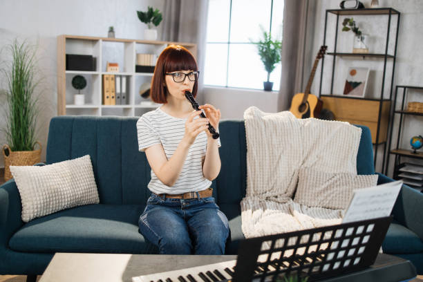 portrait d’une jeune femme jouant de la flûte. jolie fille apprenant à jouer de la flûte classique à la maison. - flute musical instrument music key photos et images de collection