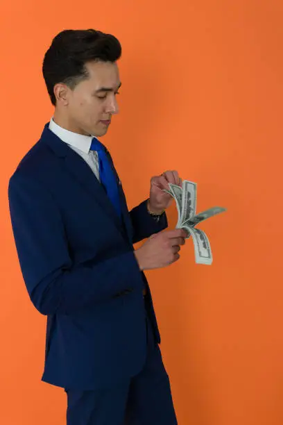 Photo of short haired elegant man holding and touching a wad of bills