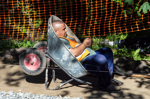 Petrozavodsk, Russia - 28 June 2022. A road worker rests in a wheelbarrow