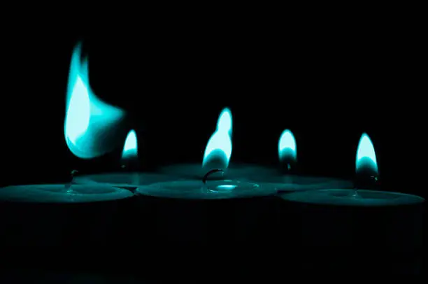 Blue-green candle light isolated black background.