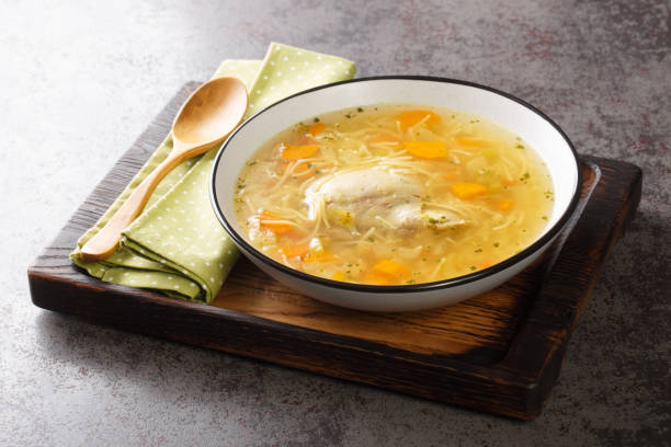 délicieux bouillon de poulet fait maison avec des nouilles et des légumes en gros plan dans une assiette. horizontal - carrot close up silverware cutting board photos et images de collection