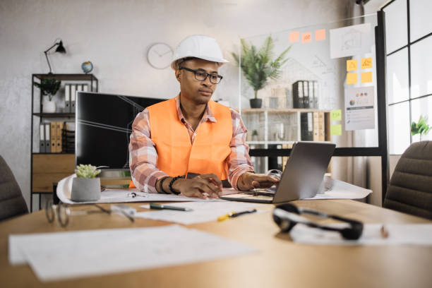 istock Focused african american man worker creating new building project sitting in modern office. 1407093324