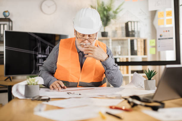 istock Architect mature man or male builder hold pen and ruler, writing and drawing architectural project. 1407093415