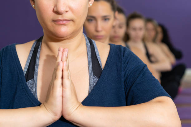 nahaufnahme einer gruppe von frauen aus verschiedenen ethnien auf mudras posieren im yoga-kurs mit den händen zusammen auf der brust - mudras stock-fotos und bilder