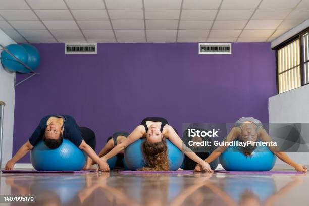 Group Of Women Practicing Pilates While Doing Exercise On A Ball Stock Photo - Download Image Now